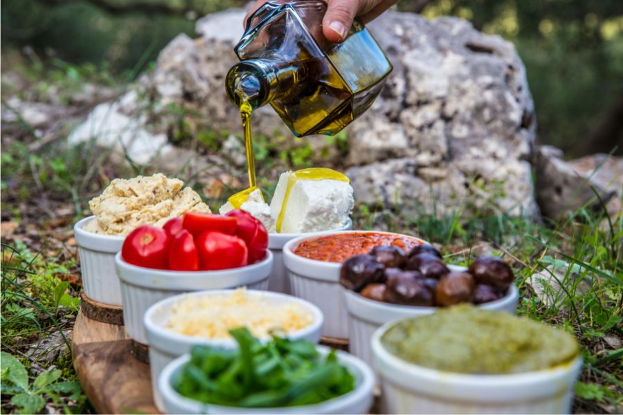 gesunde ernährung im alltag aus verschiedene mediterane speisen wie zum Beispiel Oliven, Tomaten, käse mit Olivenöl angerichtet